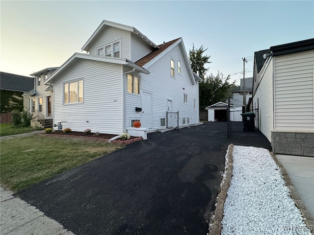 property exterior at dusk with a yard, an outbuilding, and a garage