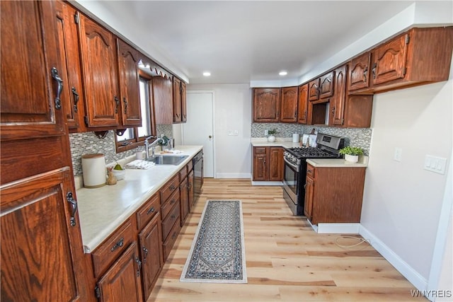 kitchen featuring backsplash, sink, light wood-type flooring, and stainless steel appliances