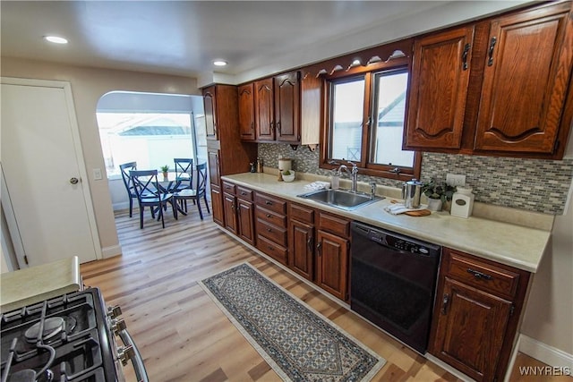 kitchen featuring backsplash, dishwasher, light wood-type flooring, and sink