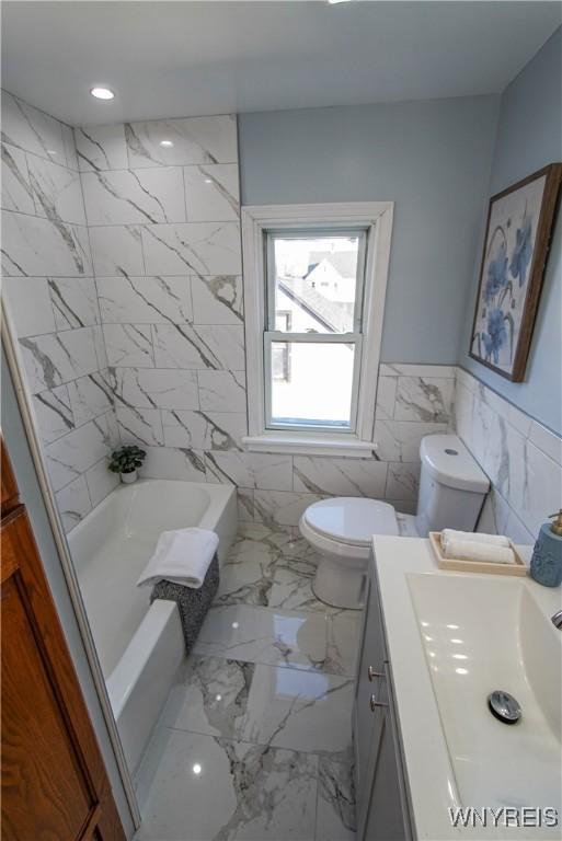 full bathroom featuring vanity, tub / shower combination, toilet, and tile walls