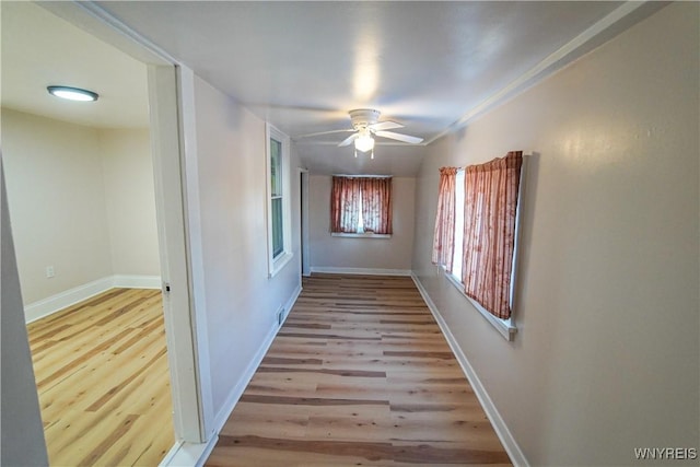 corridor featuring light wood-type flooring and crown molding