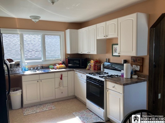 kitchen featuring white cabinetry, refrigerator, white gas stove, and sink