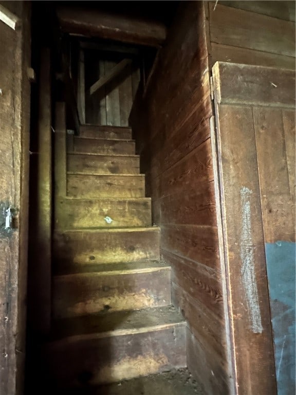 stairs featuring wood walls