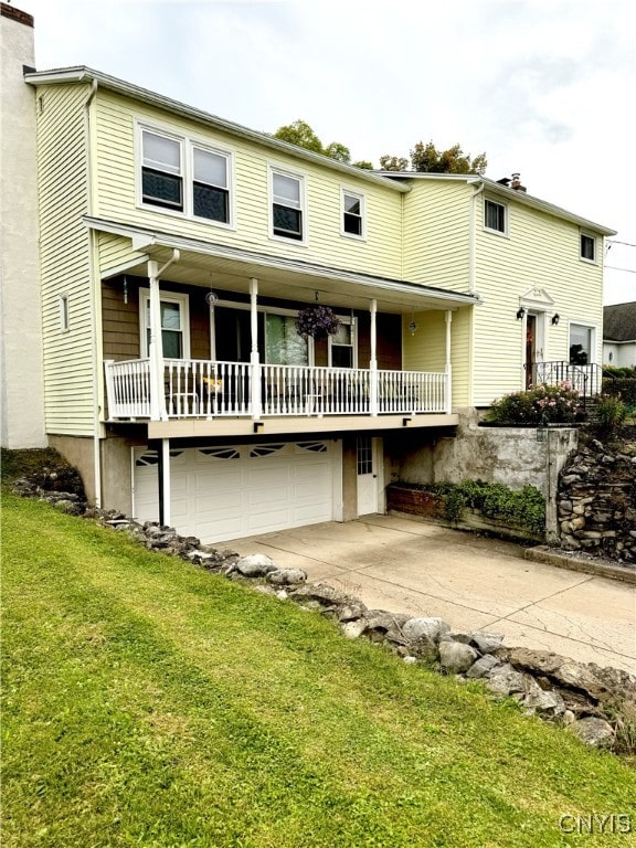 back of house featuring a yard, a porch, and a garage