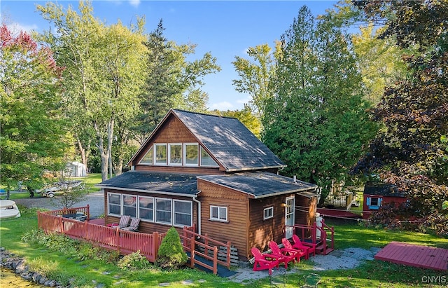 back of property featuring a wooden deck, a sunroom, and a lawn