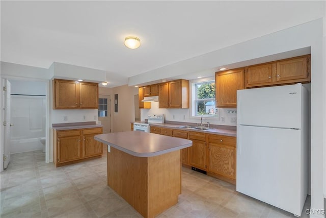 kitchen featuring white appliances, a kitchen island, and sink