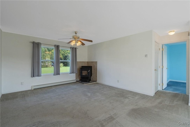 unfurnished living room with baseboard heating, a wood stove, ceiling fan, and carpet