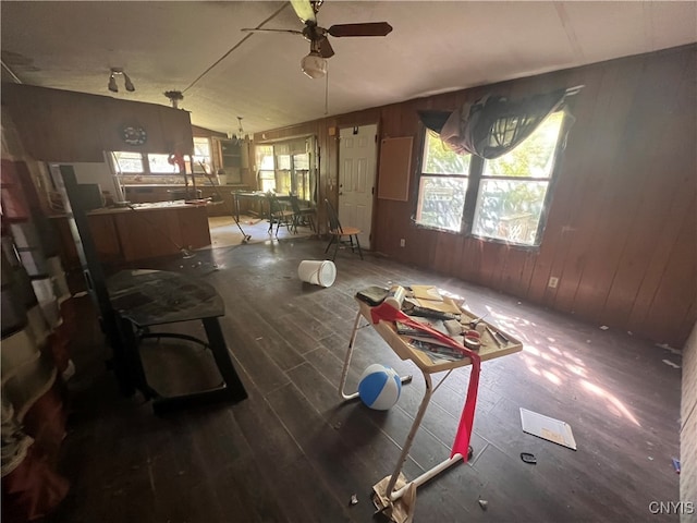 misc room featuring ceiling fan with notable chandelier, wooden walls, lofted ceiling, and dark hardwood / wood-style floors