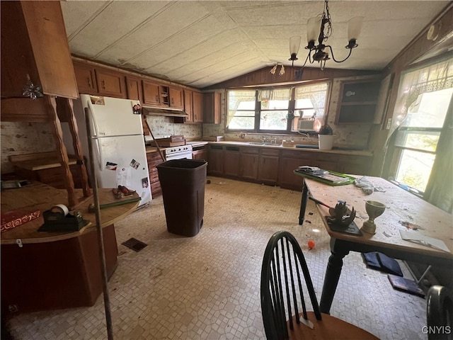 kitchen featuring pendant lighting, sink, a notable chandelier, vaulted ceiling, and white fridge