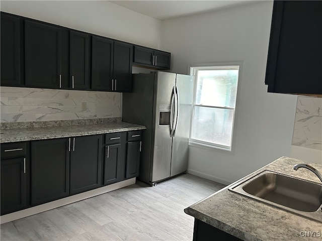 kitchen with light hardwood / wood-style floors, sink, stainless steel fridge with ice dispenser, and tasteful backsplash