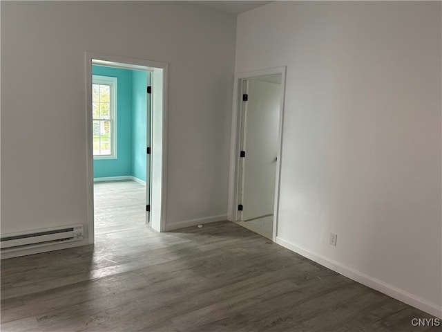 unfurnished room with dark hardwood / wood-style flooring and a baseboard heating unit