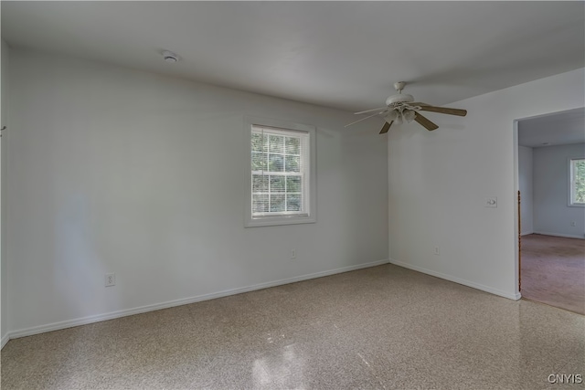 empty room with ceiling fan and a wealth of natural light