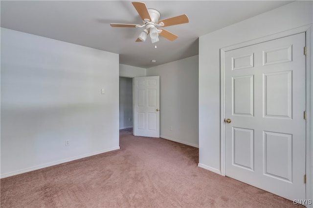 unfurnished bedroom featuring ceiling fan, light colored carpet, and a closet