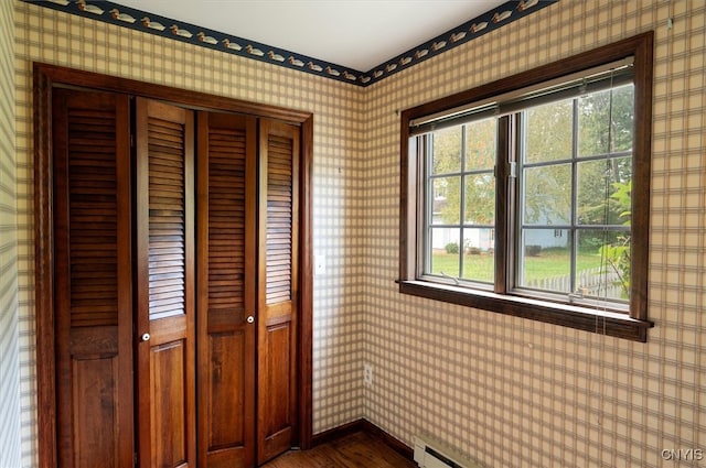 interior space with multiple windows, dark hardwood / wood-style floors, a baseboard heating unit, and a closet