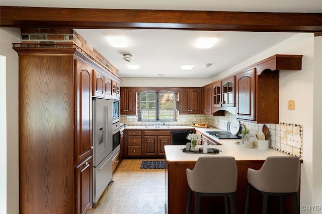 kitchen with a breakfast bar, sink, kitchen peninsula, black appliances, and backsplash