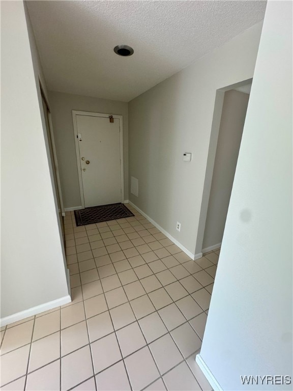 corridor with a textured ceiling and light tile patterned floors