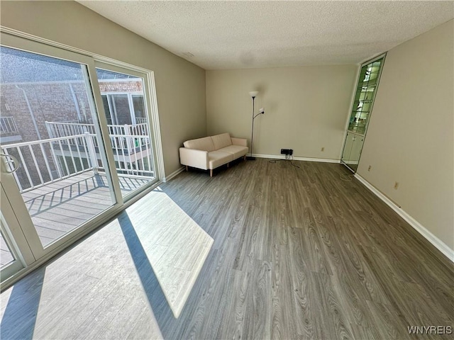 interior space with a textured ceiling, baseboards, and wood finished floors