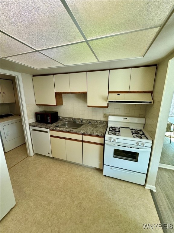 kitchen with tasteful backsplash, white gas range, exhaust hood, dishwasher, and washer / dryer