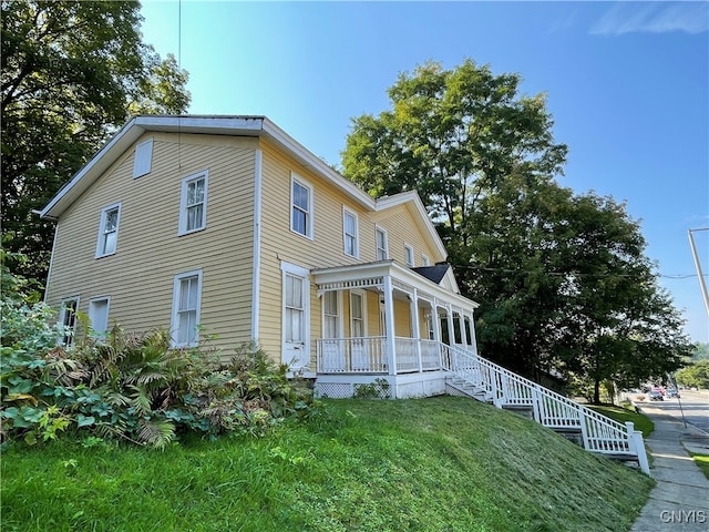 view of side of home featuring a yard and covered porch