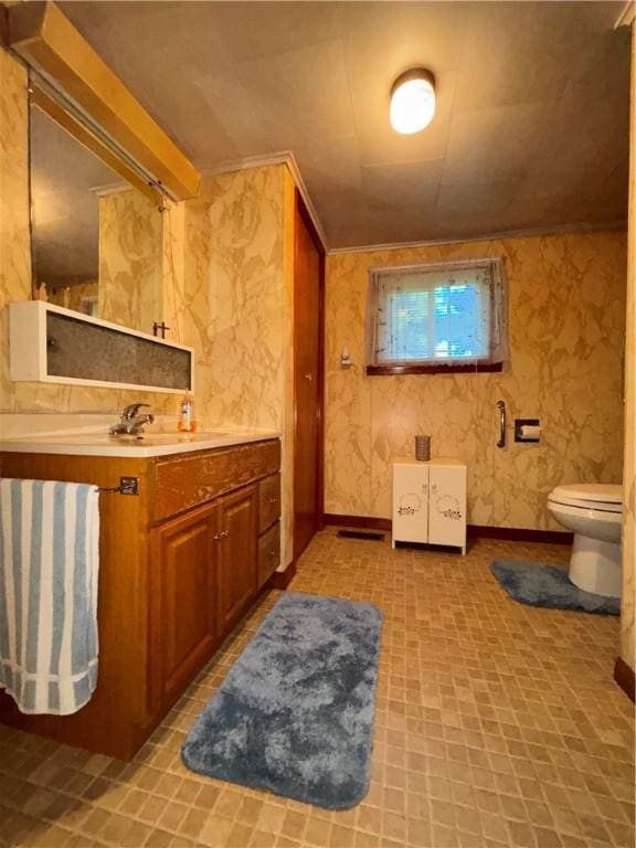 bathroom with baseboards, crown molding, toilet, and vanity