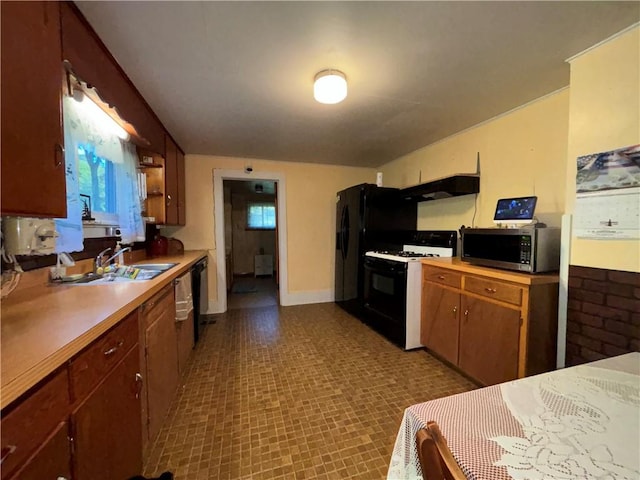 kitchen with light countertops, a sink, gas range oven, under cabinet range hood, and stainless steel microwave