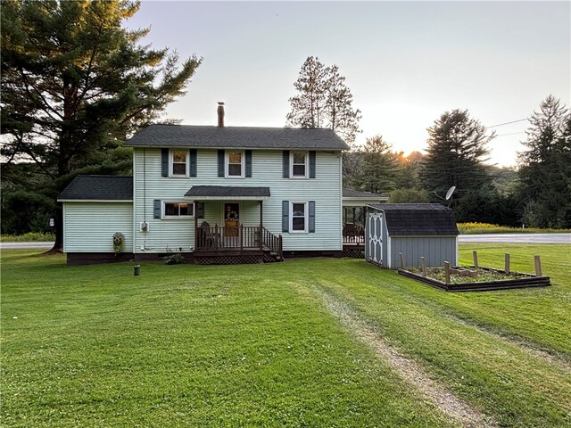 view of front facade featuring a wooden deck, a lawn, and a storage unit