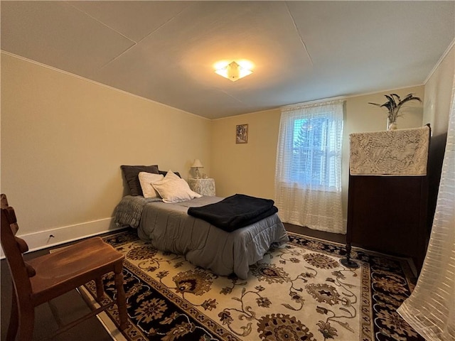 bedroom with baseboards, wood finished floors, and crown molding