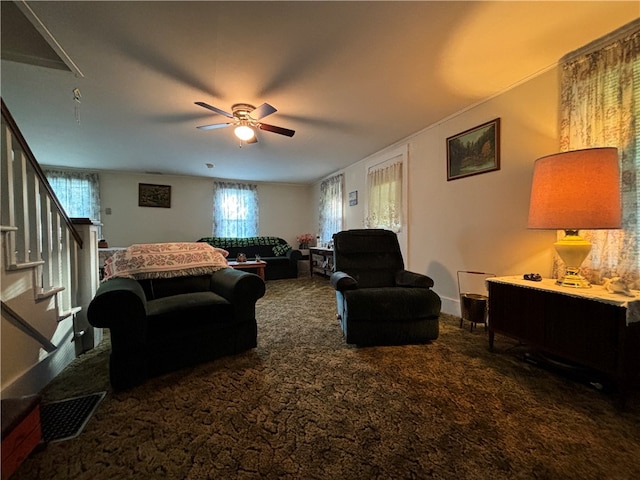 living room featuring a healthy amount of sunlight, dark carpet, and ceiling fan