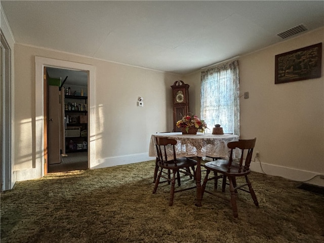 carpeted dining space with crown molding