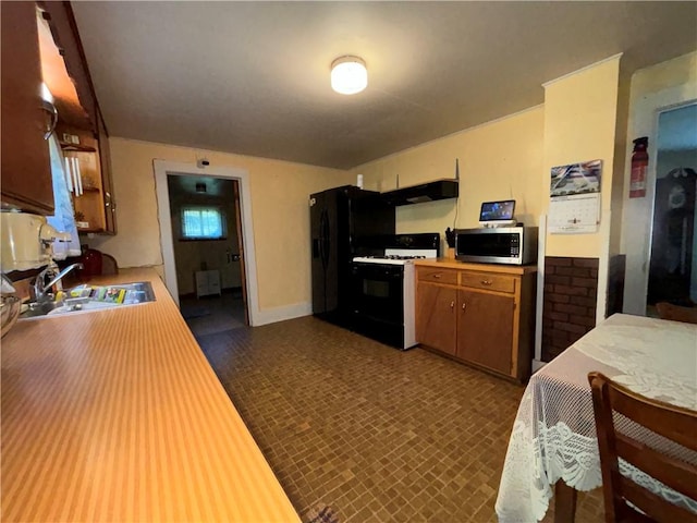 kitchen featuring light countertops, stainless steel microwave, black fridge, range with gas cooktop, and a sink