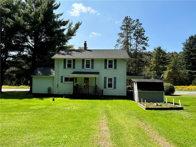 colonial house with a garden, a front lawn, and an outdoor structure