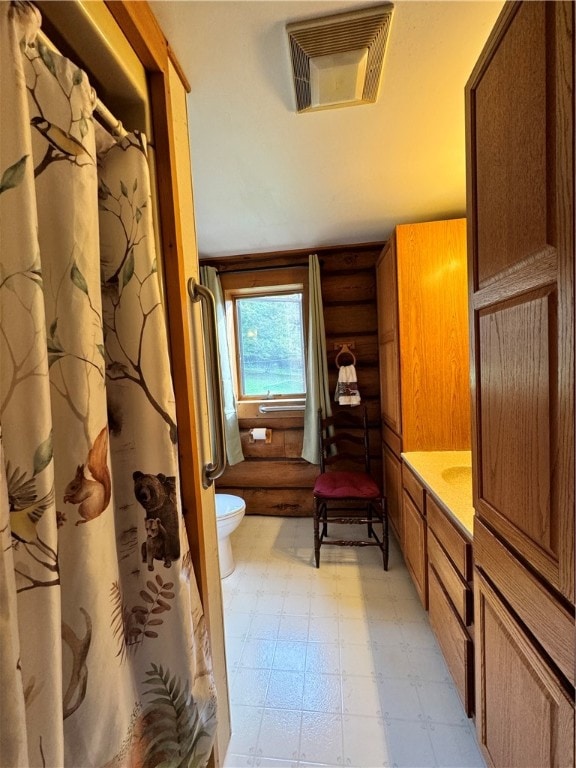 bathroom featuring rustic walls and toilet