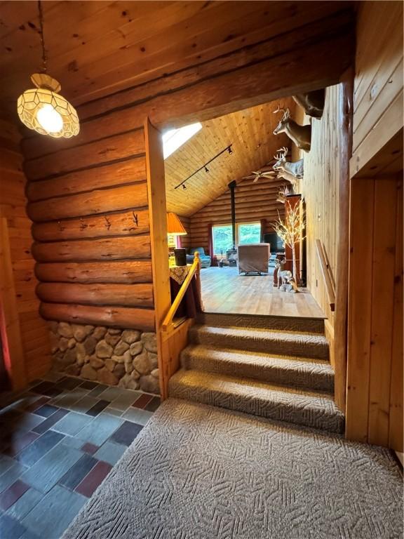 bonus room featuring log walls, lofted ceiling with beams, and wooden ceiling