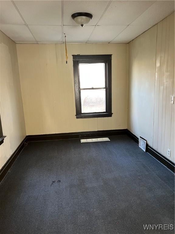 unfurnished room with a drop ceiling and dark carpet