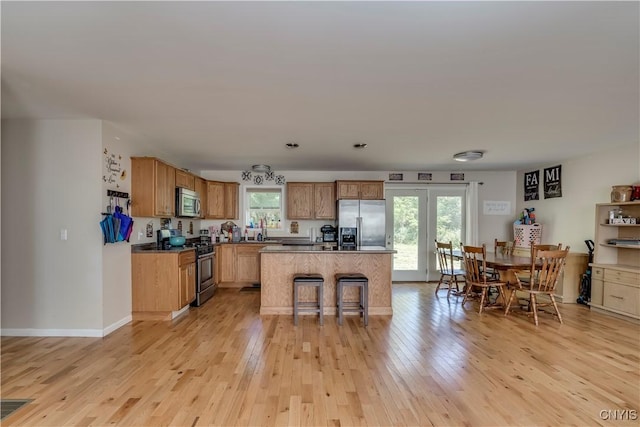 kitchen featuring a wealth of natural light, a center island, light hardwood / wood-style flooring, and appliances with stainless steel finishes