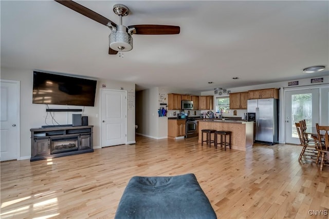 living room with light hardwood / wood-style flooring, ceiling fan, and a healthy amount of sunlight