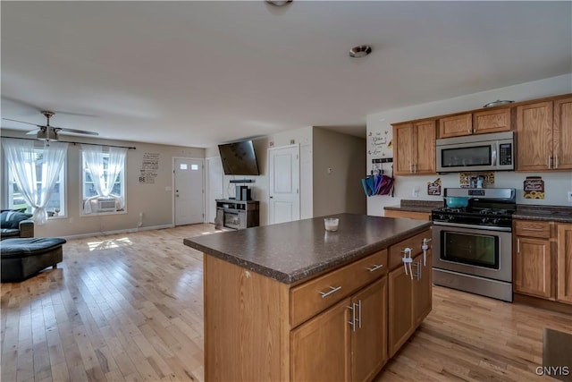 kitchen featuring ceiling fan, a center island, stainless steel appliances, and light wood-type flooring