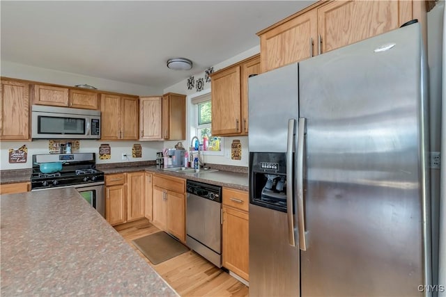 kitchen with sink, stainless steel appliances, and light wood-type flooring