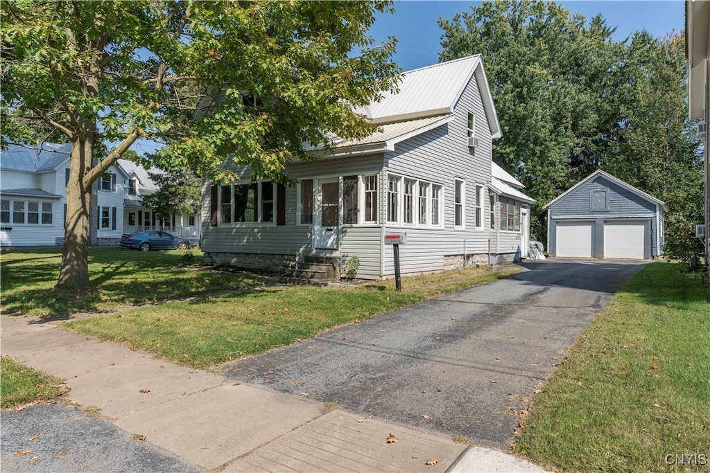 view of front of property featuring a garage, an outbuilding, and a front lawn