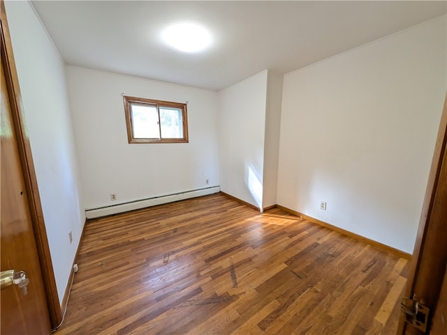 empty room with baseboard heating, crown molding, and dark hardwood / wood-style flooring