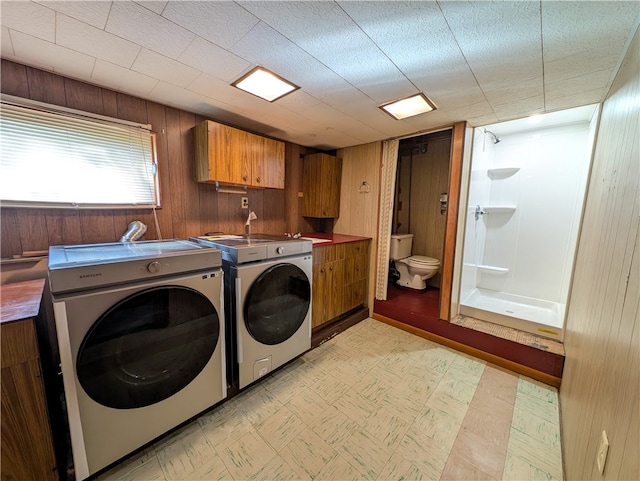 clothes washing area featuring wood walls, a textured ceiling, and washer and dryer