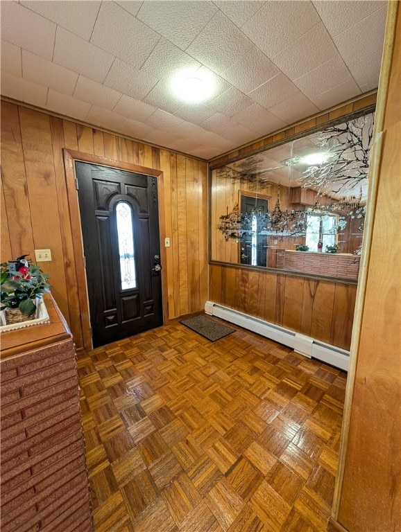 entryway featuring wooden walls, a baseboard radiator, and dark parquet flooring