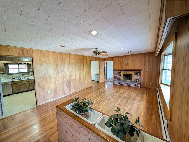 unfurnished living room featuring wood-type flooring, wood walls, ceiling fan, and a fireplace