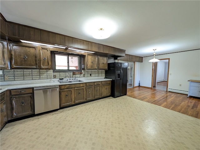 kitchen featuring black fridge, sink, stainless steel dishwasher, decorative light fixtures, and backsplash