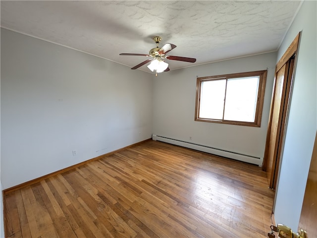 unfurnished room with ceiling fan, a baseboard radiator, and wood-type flooring