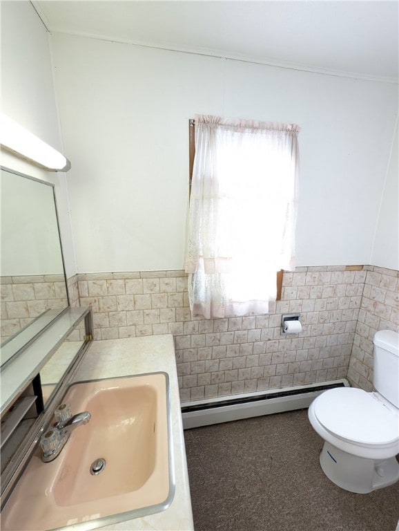 bathroom with tile walls, toilet, sink, and a baseboard radiator