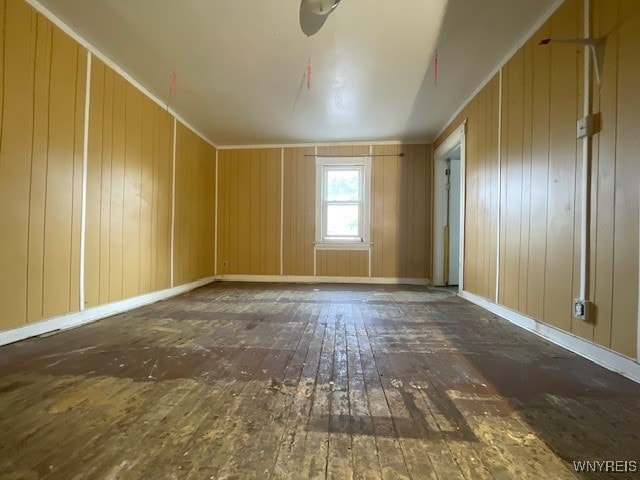 spare room featuring wooden walls and dark hardwood / wood-style flooring