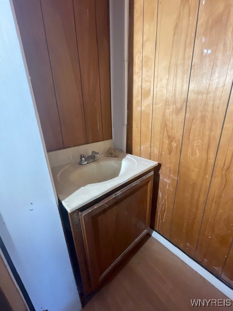 bathroom with vanity, wooden walls, and hardwood / wood-style floors