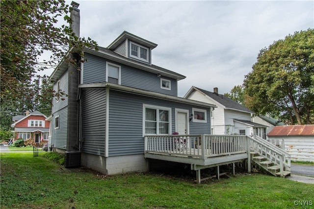 rear view of house featuring a lawn and a wooden deck