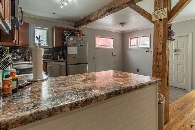 kitchen featuring light hardwood / wood-style flooring, stainless steel appliances, decorative backsplash, and a healthy amount of sunlight